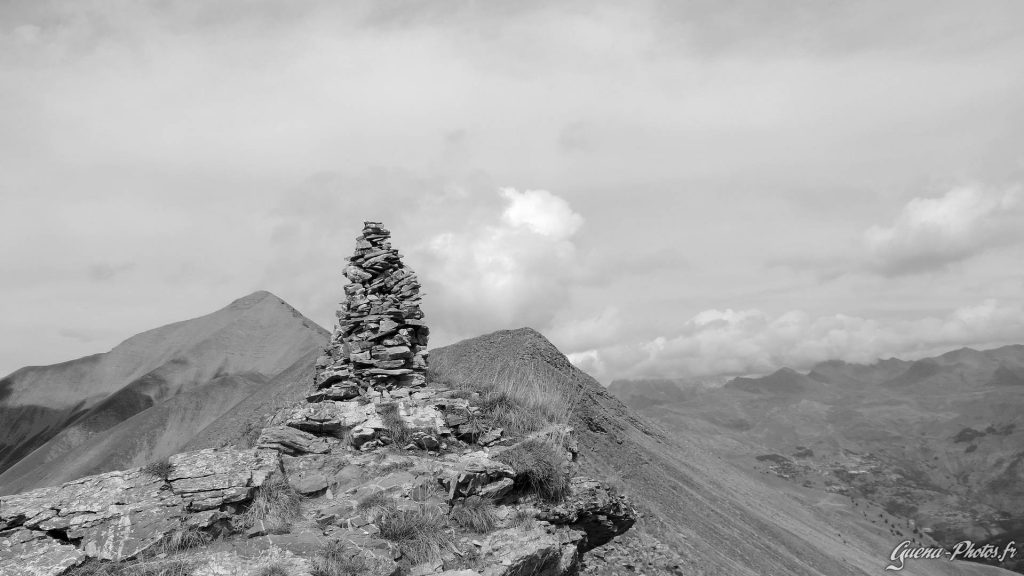 Cairn du col de Roannette, avec un aperçu en arrière plan du village d'Orcières, dans le Champsaur.