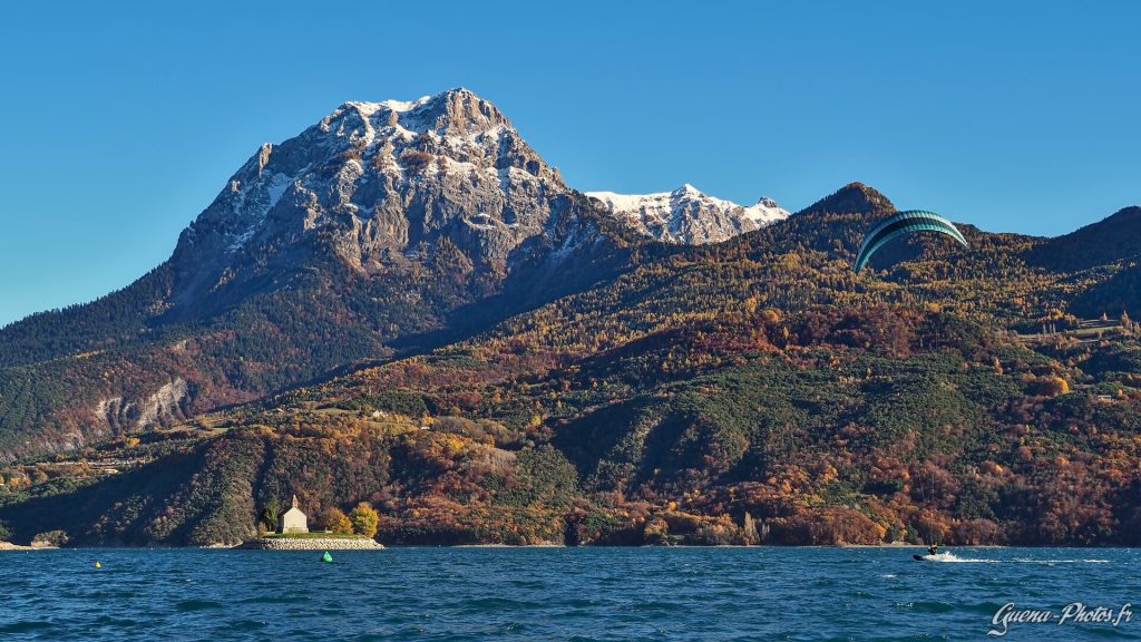 Le Grand Morgon saupoudré de neige avec à son pied le lac de Serre-Ponçon, la chapelle Saint-Michel et un Kite-surfeur